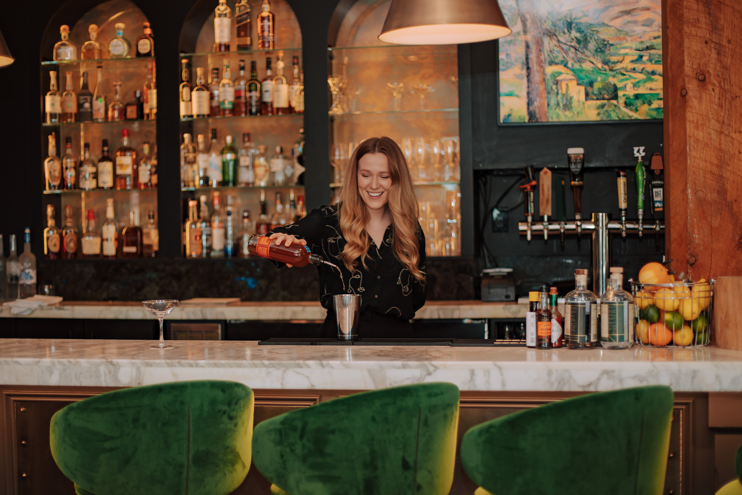 Woman creating a cocktail behind the bar at Cambridge Mill